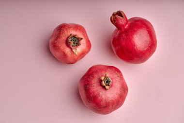 three Pomegranate isolated on pink background. Top view with copy space for your text. Flat lay. close-up photo, creative image. fresh fruits, healthy lifestyle