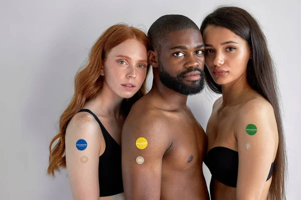 黒人男性と白人女性は腕の上にCovid 19ワクチンを示し 互いに近くに立ってポーズをとっている 市民へのワクチン接種プログラムという概念です 白に隔離され — ストック写真