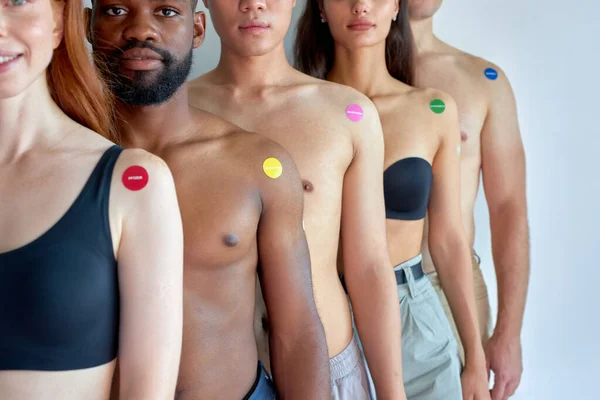 black, caucasian and asian people arms after vaccine injection, in line. prevent yourself for coronavirus, omicron, covid-19 disease outbreak in society. focus on black shirtless guy