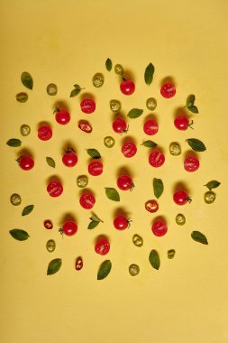 Cherry tomatoe slices and hot pepper isolated on yellow background. fresh vegetables. Top view, flat lay
