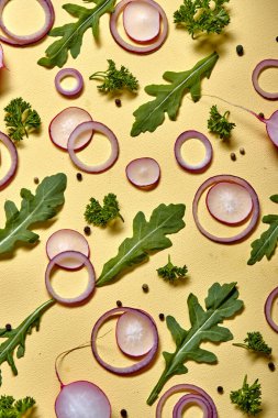 Above view on onion slices and fresh herbs isolated on yellow wall background. top view. flat lay, copy space. vegetables with vitamins for healthy lifestyle