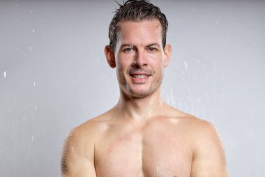 Wet muscular shirtless man isolated on gray studio background, men skin care and beauty concepts. caucasian european sexy guy enjoy bath. portriat. hygiene, daily routine concept