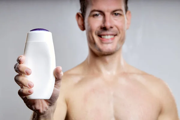 Handsome Guy Showing Bottle Gel Shampoo Advertisement Isolated Gray Studio — Fotografia de Stock