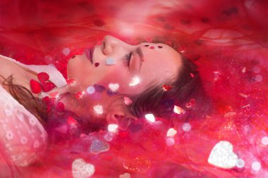 Aşık beyaz elbiseli bir kadın rüya gibi, parıldayan ışıklar ve şeffaf peçelerle çevrili..