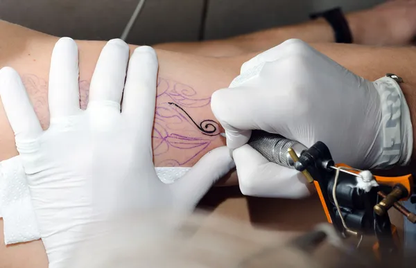 Tattoo artist makes the tattoo on arm — Stock Photo, Image