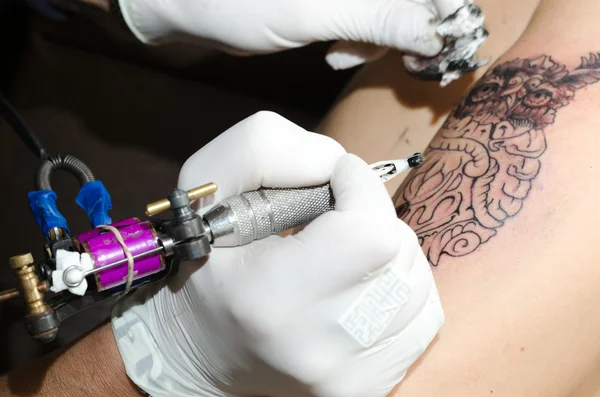 Tatuaje artista hace el tatuaje en el brazo — Foto de Stock