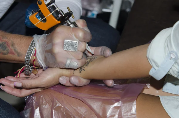 Tattoo artist makes the tattoo on arm — Stock Photo, Image