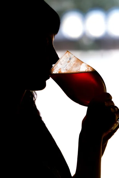 一个女孩喝樱桃啤酒的剪影 图库图片