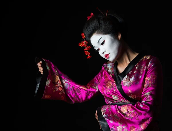 Porträtt av geisha presentera något isolerat på svart — Stockfoto