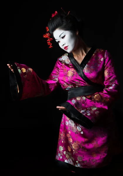 Porträtt av geisha presentera något isolerat på svart — Stockfoto