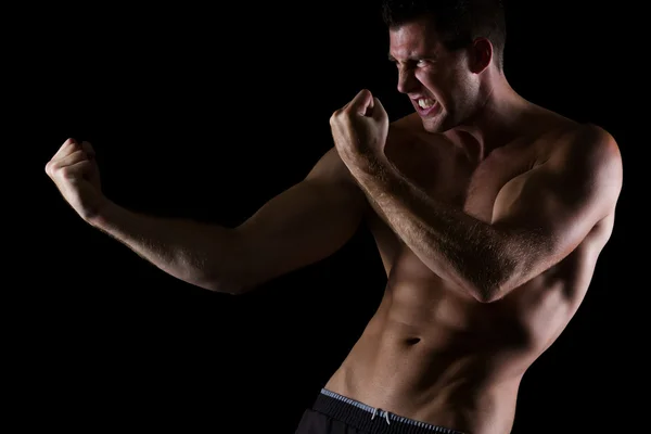 Enojado muscular hombre en ataque pose en negro —  Fotos de Stock
