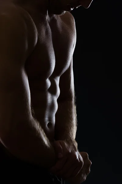 Closeup on man showing muscular body on black — Stock Photo, Image