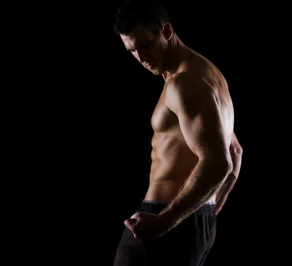 Strong muscular athlete posing on black — Stock Photo, Image