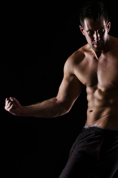 Forte homem muscular posando no preto — Fotografia de Stock