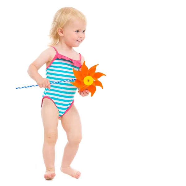 Happy baby in swimsuit with pinwheel looking on copy space — Stock Photo, Image