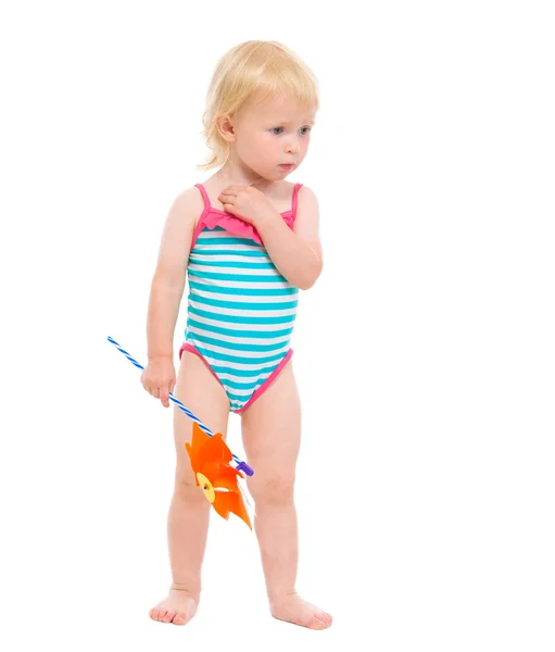 Nachdenkliches Baby im Badeanzug mit Windrad — Stockfoto