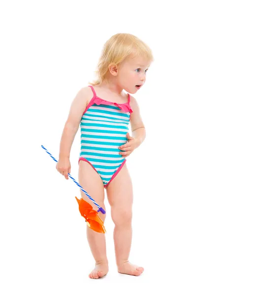 Surprised baby in swimsuit with pinwheel looking on copy space — Stock Photo, Image