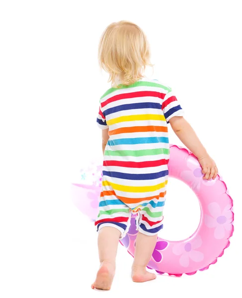 Baby in swimsuit playing with inflatable ring and beach ball. Re — Stock Photo, Image