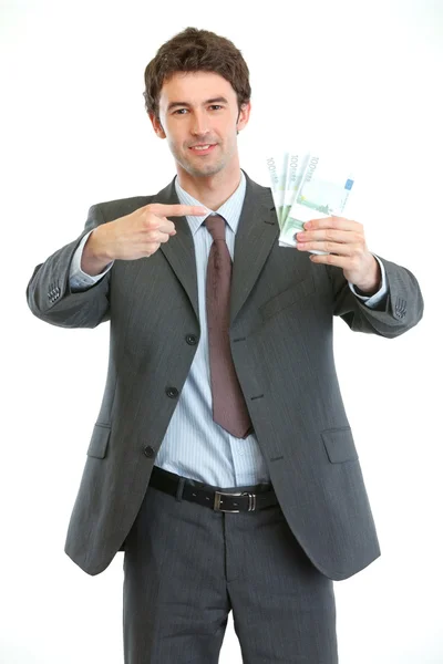 Smiling businessman pointing on packs of euros — Stock Photo, Image