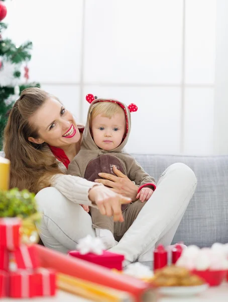 Sonriente joven madre pasando la Navidad con el bebé y señalando o —  Fotos de Stock