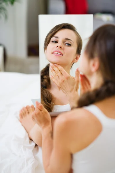 Gelukkig jonge vrouw zittend op bed en op zoek op spiegel — Stockfoto