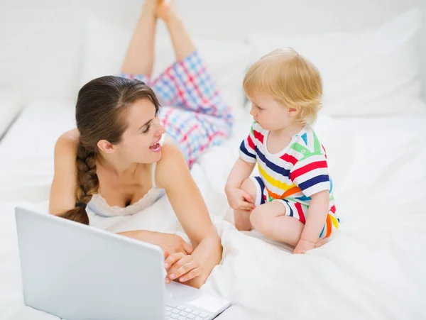 Young mother showing baby something in laptop — Stock Photo, Image