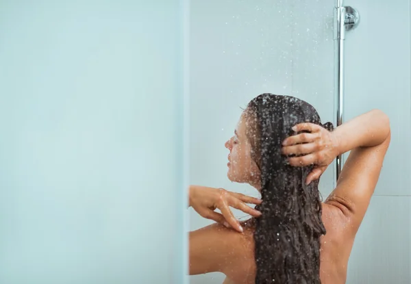 Женщина с длинными волосами принимает душ. Вид сзади — стоковое фото