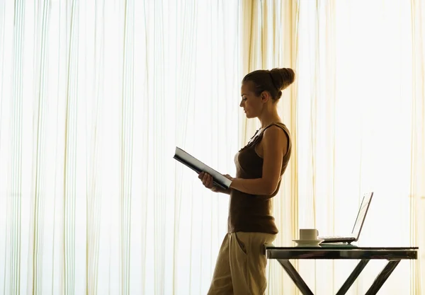 Jeune femme lecture livre appuyé contre la table — Photo