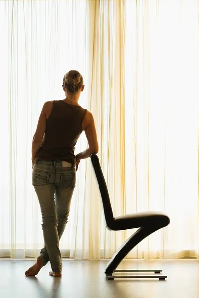 Mujer joven apoyada en una silla moderna. Vista trasera — Foto de Stock