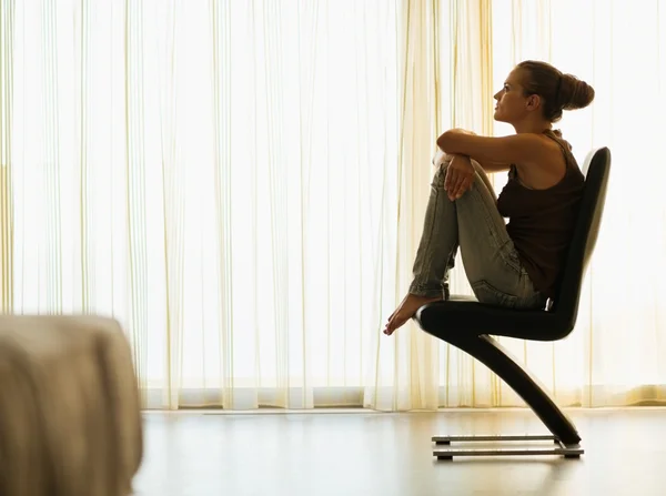 Mujer joven sentada en una silla moderna cerca de la ventana —  Fotos de Stock