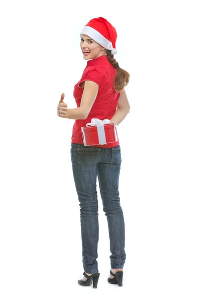 Felice giovane donna nascondendo scatola regalo di Natale dietro la schiena e s — Foto Stock