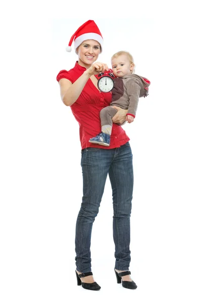 Mutter mit Weihnachtsmütze hält Baby und Wecker — Stockfoto