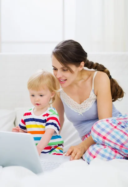Moderne jeune mère et bébé en utilisant un ordinateur portable — Photo