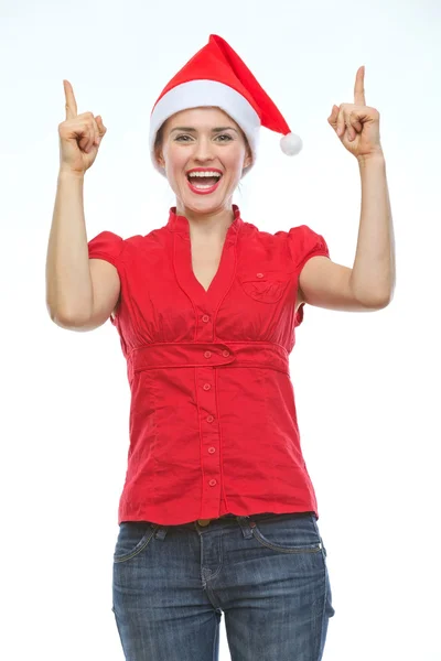 Smiling young woman in Christmas hat pointing up Stock Photo