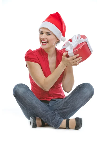 Happy young woman in Christmas hat sitting on floor with present Royalty Free Stock Photos
