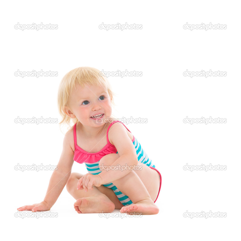Curious baby in swimsuit sitting on floor and looking on copy sp