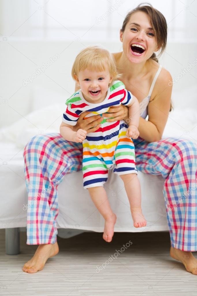Portrait of happy young mother with baby in bedroom