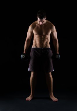 siyah üzerine dumbbell tutarak güçlü kas adam