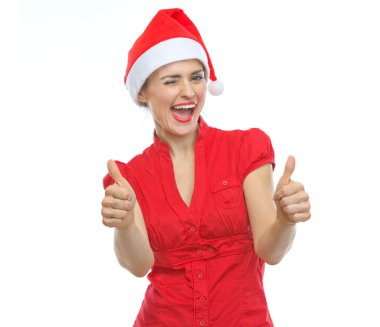 mutlu genç kadın göz kırpıyor ve başparmak gösterilen Noel şapka