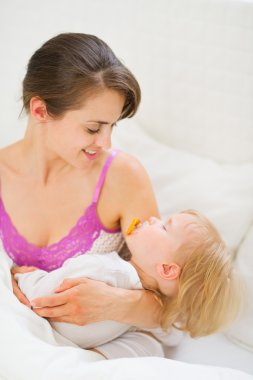uyuyan bebek tutan gülümseyen genç anne