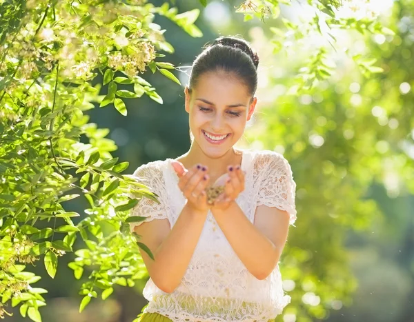 Mujer joven sosteniendo semillas en palmeras en el bosque — Foto de Stock