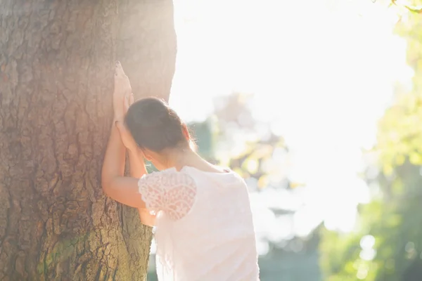 Giovane femmina appoggiata all'albero. Vista posteriore — Foto Stock