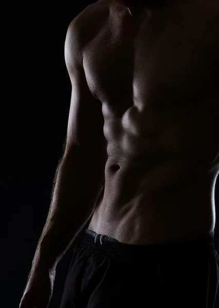 Primer plano en el torso masculino muscular con músculos abdominales en negro — Foto de Stock