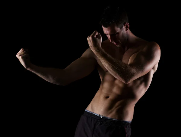 Muscular man in attack pose on black — Stock Photo, Image