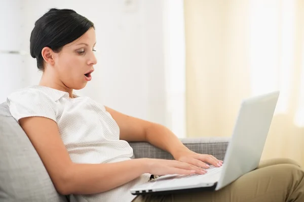 Surpreendida jovem mulher usando laptop na sala de estar — Fotografia de Stock