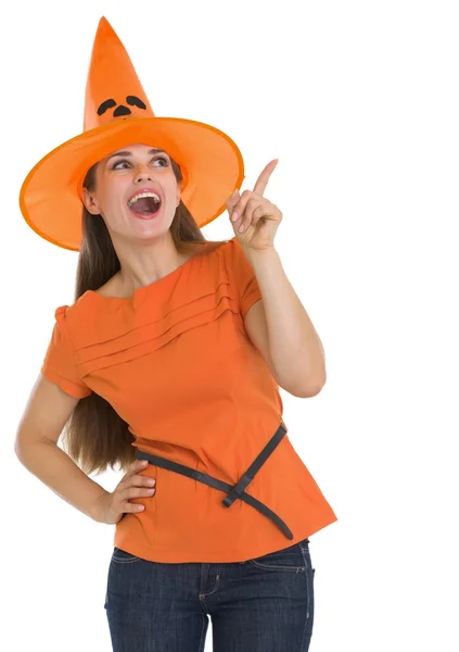 Mujer joven feliz en sombrero de Halloween apuntando en el espacio de copia —  Fotos de Stock