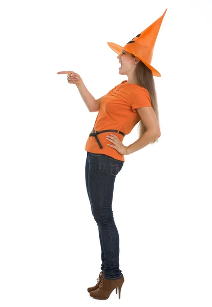 Молодая женщина в шляпе на Хэллоуин указывает на пространство для копирования — стоковое фото