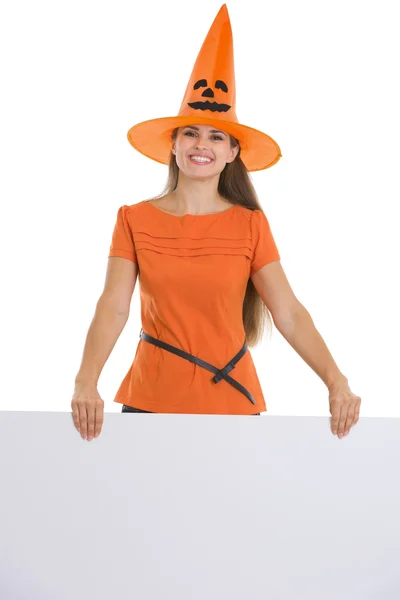 Vrouw in halloween hoed, bedrijf leeg reclamebord — Stockfoto