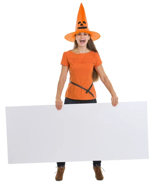 Lachende vrouw in halloween hoed, bedrijf leeg reclamebord — Stockfoto