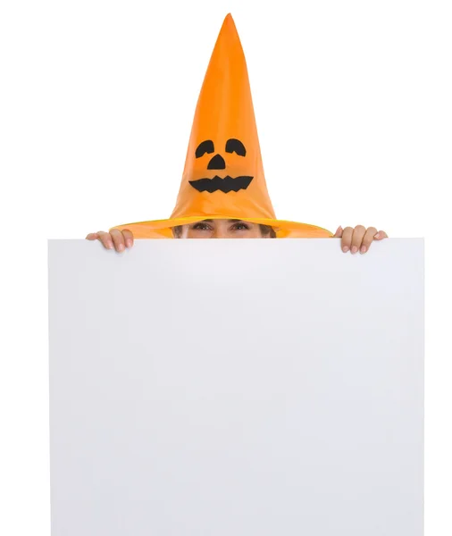 Woman in Halloween hat looking out from blank billboard — Stock Photo, Image